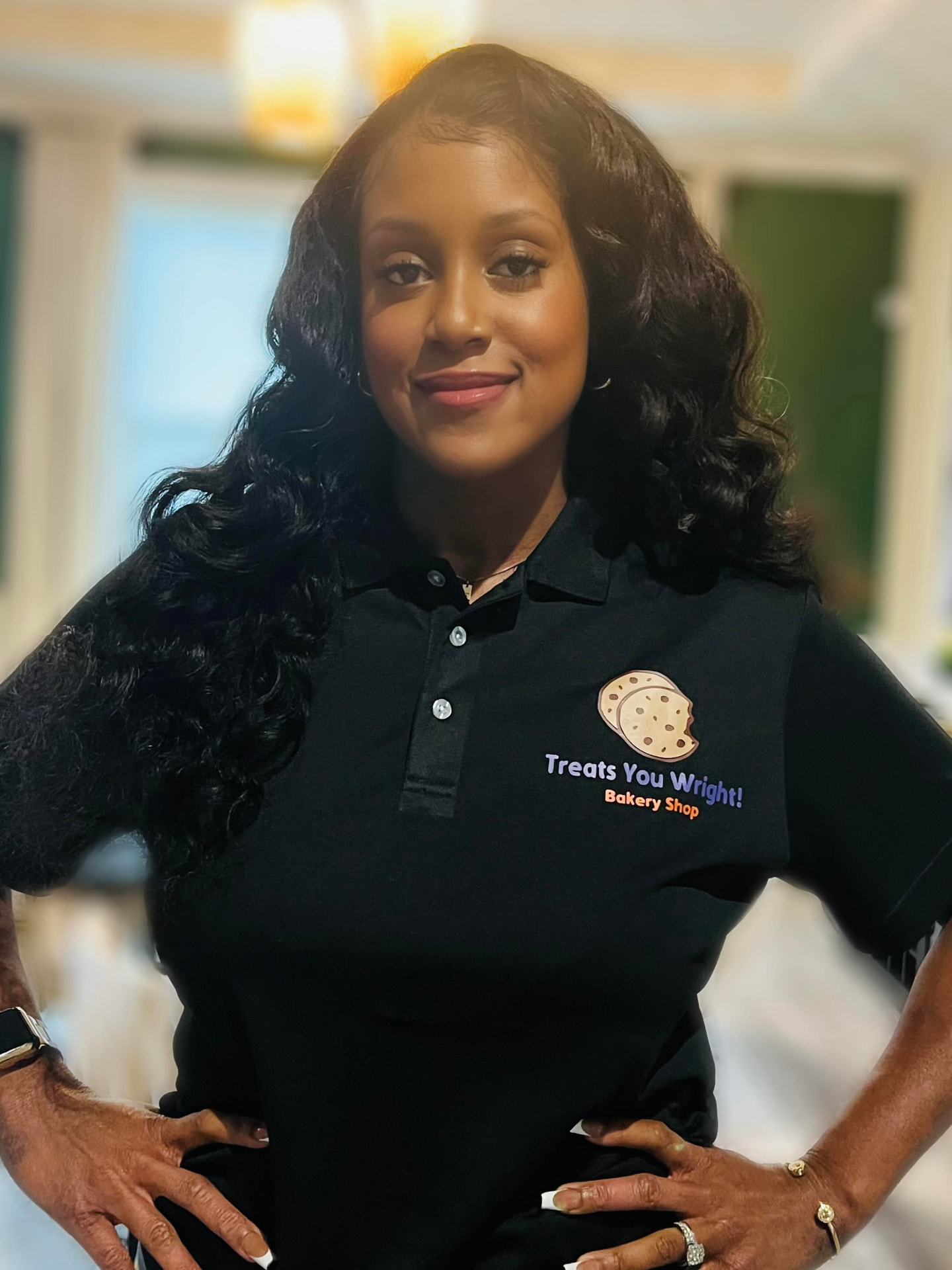 Portia Taylor, owner of Treats You Wright, smiling in her black branded bakery polo shirt